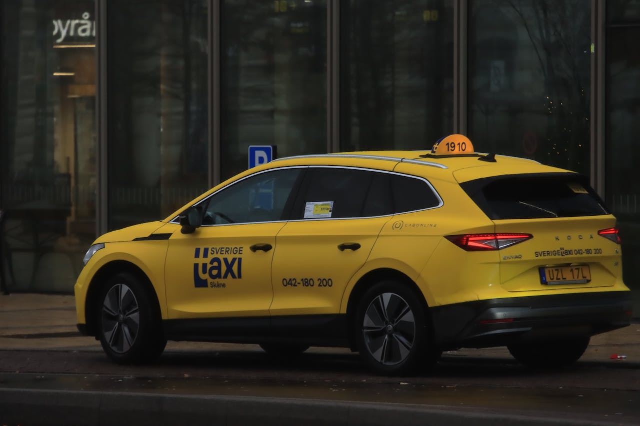 A yellow taxi cab waits on an urban street, showcasing public transportation.